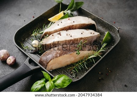 Raw halibut fish steaks with herbs and lemon prepared for cooking in a grill pan. Healthy omega 3 unsaturated fats source good for brain and mental clarity