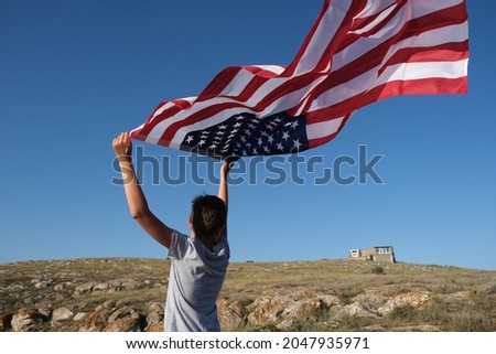 A boy holding waving US flag, beeng a patriot concept.