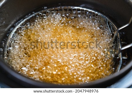 top view. oil boiling in a deep fryer. in the basket of the fryer cook shrimp in batter or potatoes. gadgets for the kitchen. cooking seafood in boiling vegetable oil. Royalty-Free Stock Photo #2047948976