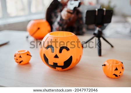 Background image of variations Halloween buckets with smartphone set up on table, livestream background
