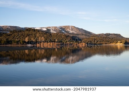 Symmetry in nature. Enchanting view of the Andes mountain range, forest and sky, and the reflection in lake Aluminé water surface at sunset, in Villa Pehuenia, Neuquén, Patagonia Argentina. Royalty-Free Stock Photo #2047981937