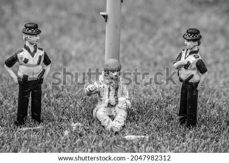 Closeup of tiny model homeless man with police