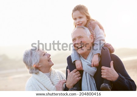 Grandparents And Granddaughter Walking On Winter Beach