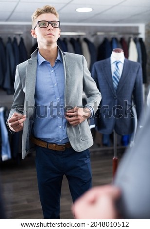 Man costumer in the glasses trying business style jacket in the shop