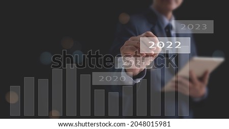 Concept of economic recovery in year 2022 after the fall due to the covid 19 coronavirus pandemic. Businessman pointing 2022 button with increase graph corporate future growth plan and business goals