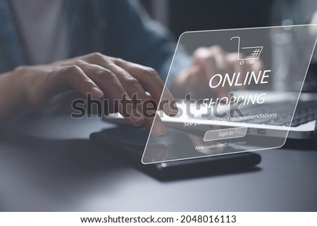 Woman using mobile phone and laptop computer for online shopping via mobile app and signing in products store website with shopping cart on virtual screen