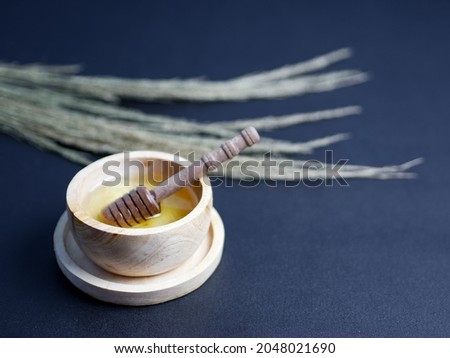 fresh honey in a small wooden bowl on black background, healthy and herbal food concept