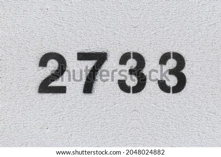 Black Number 2733 on the white wall. Spray paint. Number two thousand seven hundred thirty three.