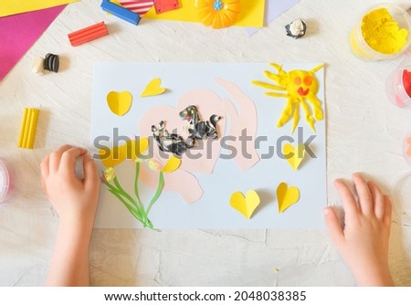 Child making card from colorful paper and plasticine. Card for International  Homeless Animals day. Pets adoption concept. Explain to the child through play and creativity about important things