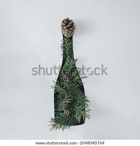 Champagne bottle decorated with pine foliage and cones over a white background with copyspace for Christmas and holiday concepts or greeting card