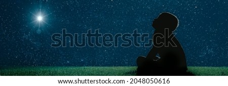 child sit on the grass at night and look at the  christmas night sky