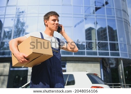 Deliveryman in uniform holds parcel and phone
