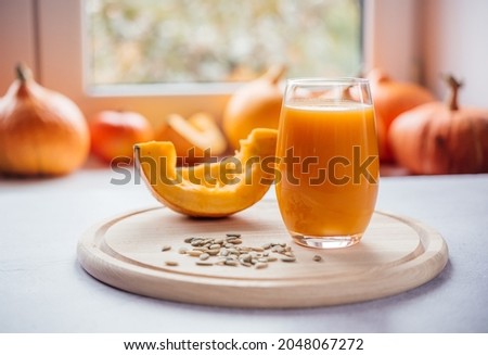 A glass of pumpkin juice with pumpkin seeds on a windowsill