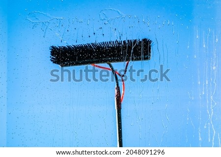 Window cleaning using telescopic water brush and wash system. Commercial window cleaning from the outside with sky in background. Defocused Royalty-Free Stock Photo #2048091296