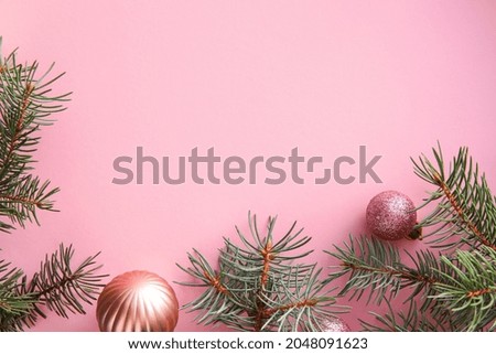 Fir branches with Christmas balls on pink background