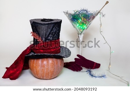 Halloween set. A large top hat on a ripe pumpkin and a magic cocktail in a huge glass martini glass. Bottom pair of red gloves

