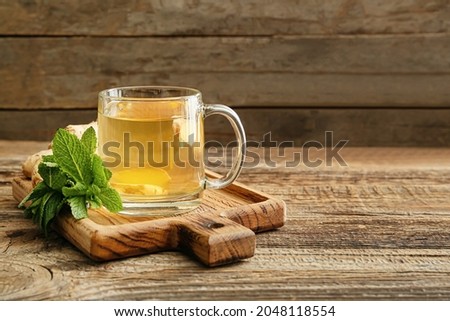 Cup of tea with ginger and mint on wooden background