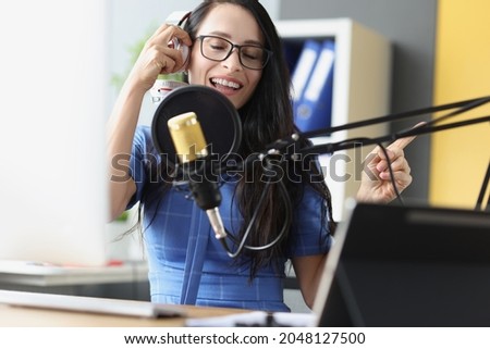 Young beautiful woman singing into microphone with headphones