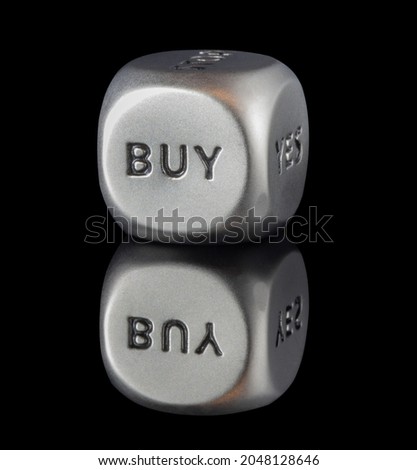 a gray metal decisionn dice on the edge is written buy, isolated on black, reflection in black glass