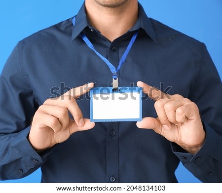 Young man with blank badge on color background, closeup