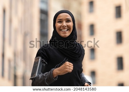 Portrait Of Happy Young Islamic Lady In Hijab Jogging Outdoors, Motivated Athletic Muslim Woman Wearing Modest Sportswear Training On City Streets, Enjoying Running, Closeup Shot, Free Space