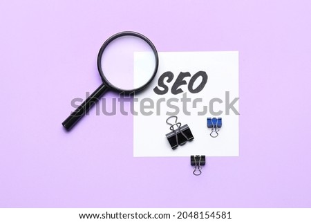 Paper sheet with abbreviation SEO and magnifier on color background