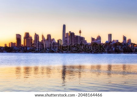 Skyline of City of Sydney over Inner West waterfront with reflection in Parramatta river waters at sunrise. Royalty-Free Stock Photo #2048164466