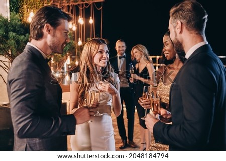 Group of people in formalwear communicating and smiling while spending time on luxury party Royalty-Free Stock Photo #2048184794