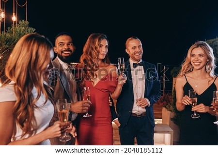 Group of beautiful people in formalwear communicating and smiling while spending time on luxury party Royalty-Free Stock Photo #2048185112