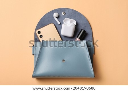 Stylish women's bag and different stuff on pale orange background, top view Royalty-Free Stock Photo #2048190680