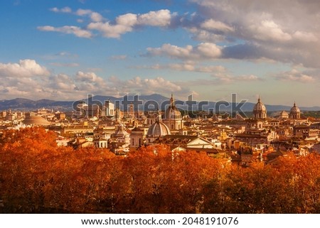 Autumn in Rome. View of the historical center skyline just before sunset with old monuments, baroque domes and red leaves