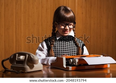 Little girl runs a business. She is typing on typewriter machine. Business concept.