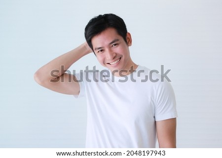 Studio portrait shot of Asian young handsome smart shying embarrassing guy male model in casual clothing smiling show teeth feeling sorry look at camera holding hand on head on white background. Royalty-Free Stock Photo #2048197943