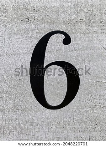 A Close Up Of A Hand Painted Number Six In Black On A Weathered And Distressed White Painted Background