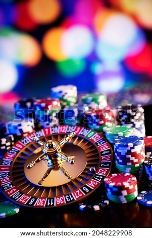 Gambling and casino concept. Roulette wheel, poker chips, cards, dice, bokeh background.