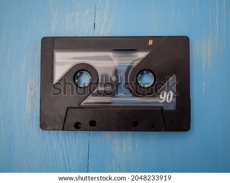 Single Black Retro Audio Tape Cassettes on a Blue Wooden Background