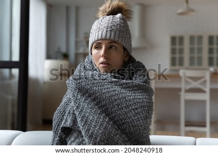 Unhealthy young Caucasian woman in warm hat and blanket at home feel cold sick have corona virus or flu. Unwell ill millennial female suffer freeze, struggle with high temperature and influenza. Royalty-Free Stock Photo #2048240918