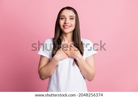 Photo portrait young woman keeping hands on chest thankful isolated pastel pink color background