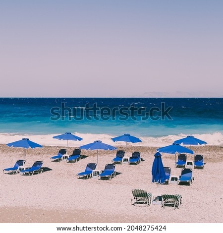 Beach with sand, blue sunbeds and sea. Retro styled concept