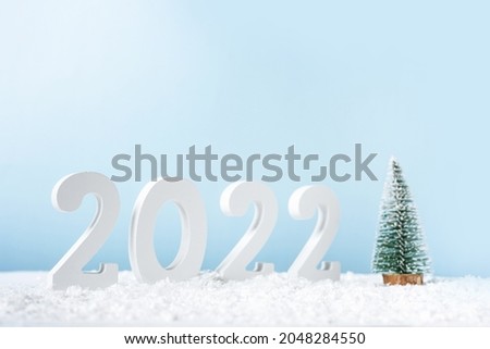 Happy New Year 2022. Decorative white number 2022, fir tree and snow isolated on blue background. Greeting christmas card with copy space.
