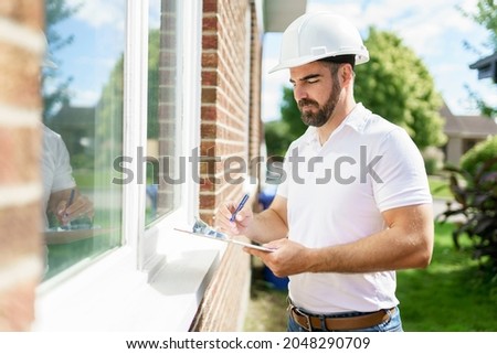 A man with a white hard hat holding a clipboard, inspect house Royalty-Free Stock Photo #2048290709