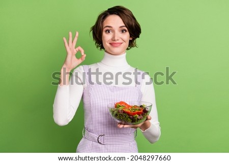 Photo of young girl happy positive smile healthy food vegetables salad sho okay alright ad sign isolated over green color background