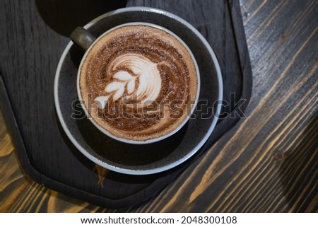 A cup of coffee latte art on the wooden table in coffee shop vintage style is the most popular drink for modern people. Concept refreshment for life.