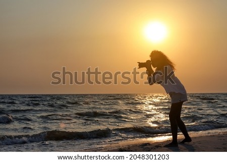 Photographer taking photo of sea with professional camera at sunset