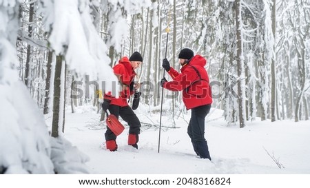 Mountain rescue service on operation outdoors in winter in forest, finding person after avalanche. Royalty-Free Stock Photo #2048316824
