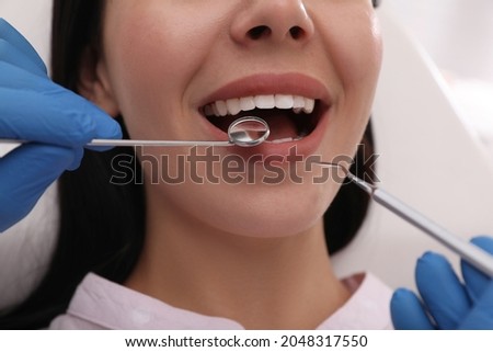 Dentist examining young woman's teeth, closeup view