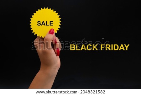 a woman's hand holds a yellow sticker with the inscription discount, a layout on the theme of Black Friday.