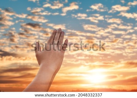 Praying hands with faith in religion and belief in God over blur sunset sky background.