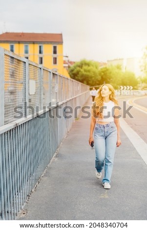 Young long blonde hair caucasian woman walking outdoor strolling enjoying city living