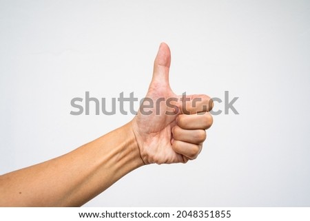 Closeup of male hand showing thumbs up sign on white background, selective focus, Horizontal orientation, copy space.